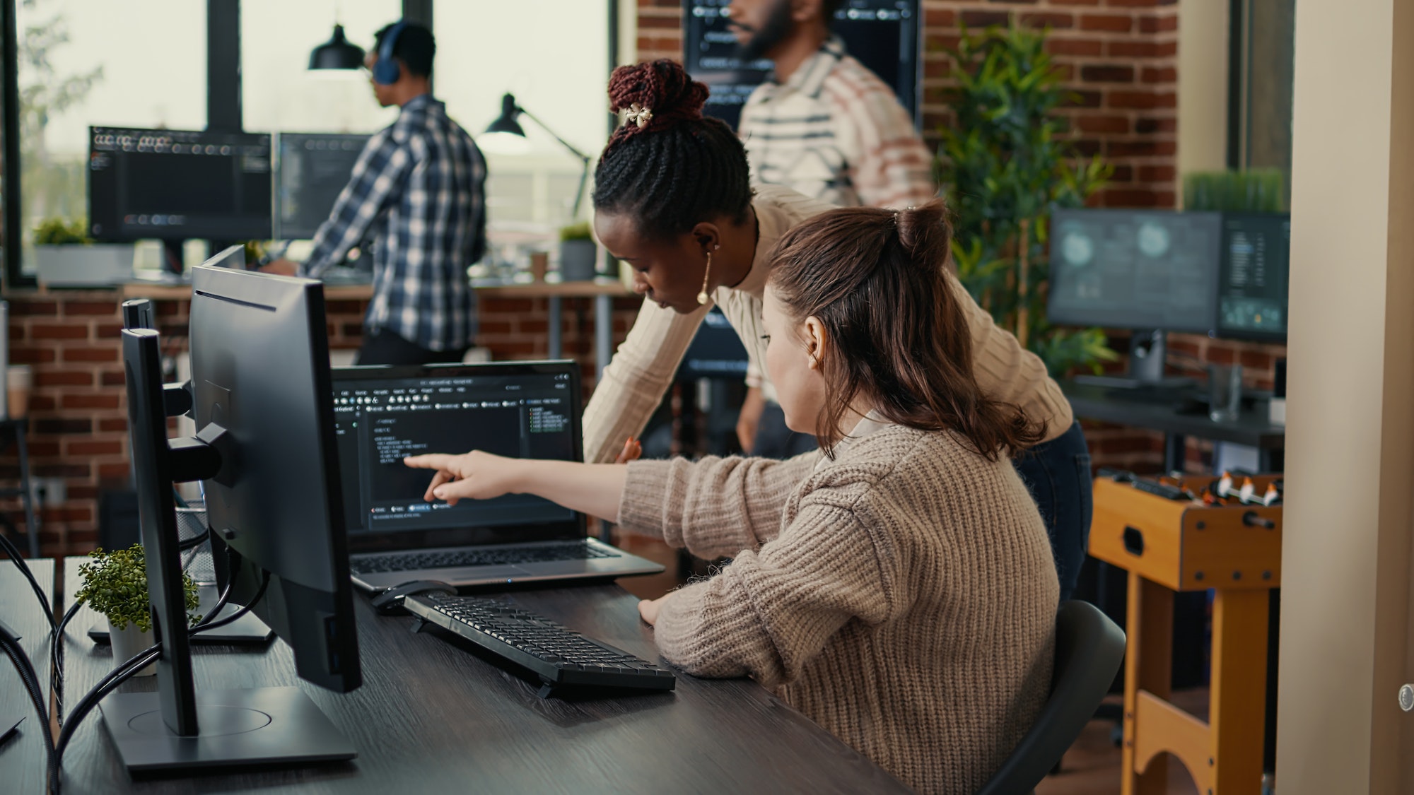 Two software coders analyzing source code looking for errors running on laptop screen